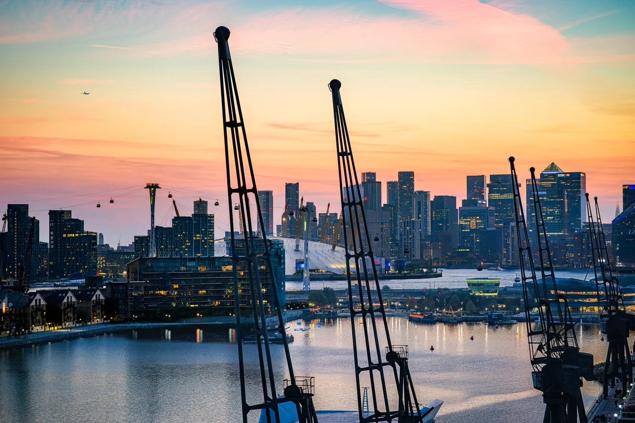 Royal Victoria Dock cranes silhouetted against the O2 and Canary Wharf at sunset