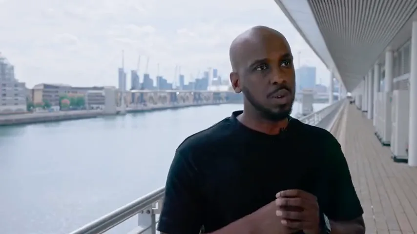 A contributor speaking on an ExCeL London balcony above the Royal Docks