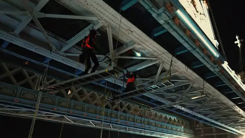 A maintenance worker positioned against the Tower Bridge structure